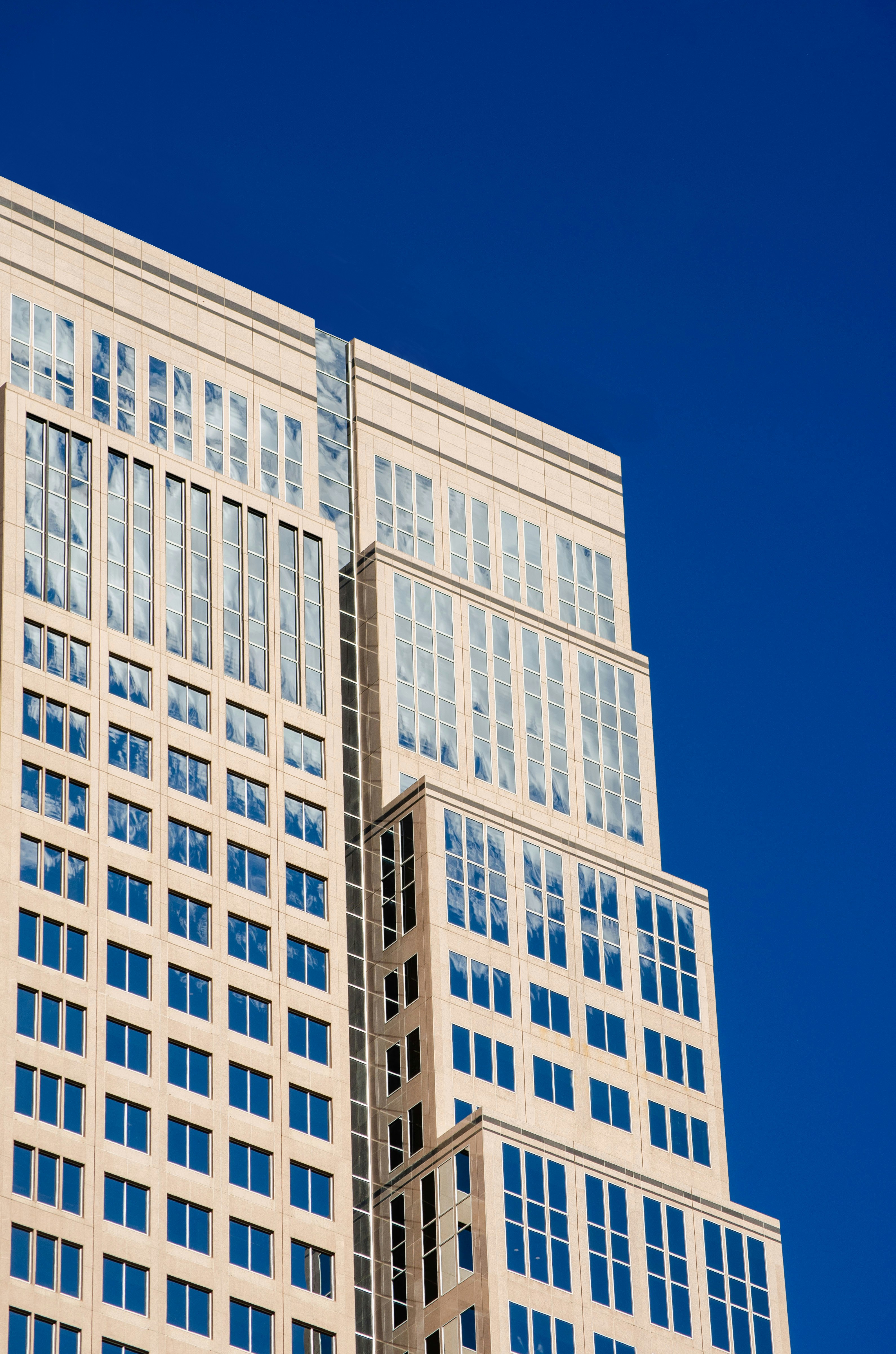 Photo by Dmytro Yarish on Unsplash - This image showcases a high-rise building with a grid of large windows reflecting the sky and clouds, emphasizing modernity and symmetry.