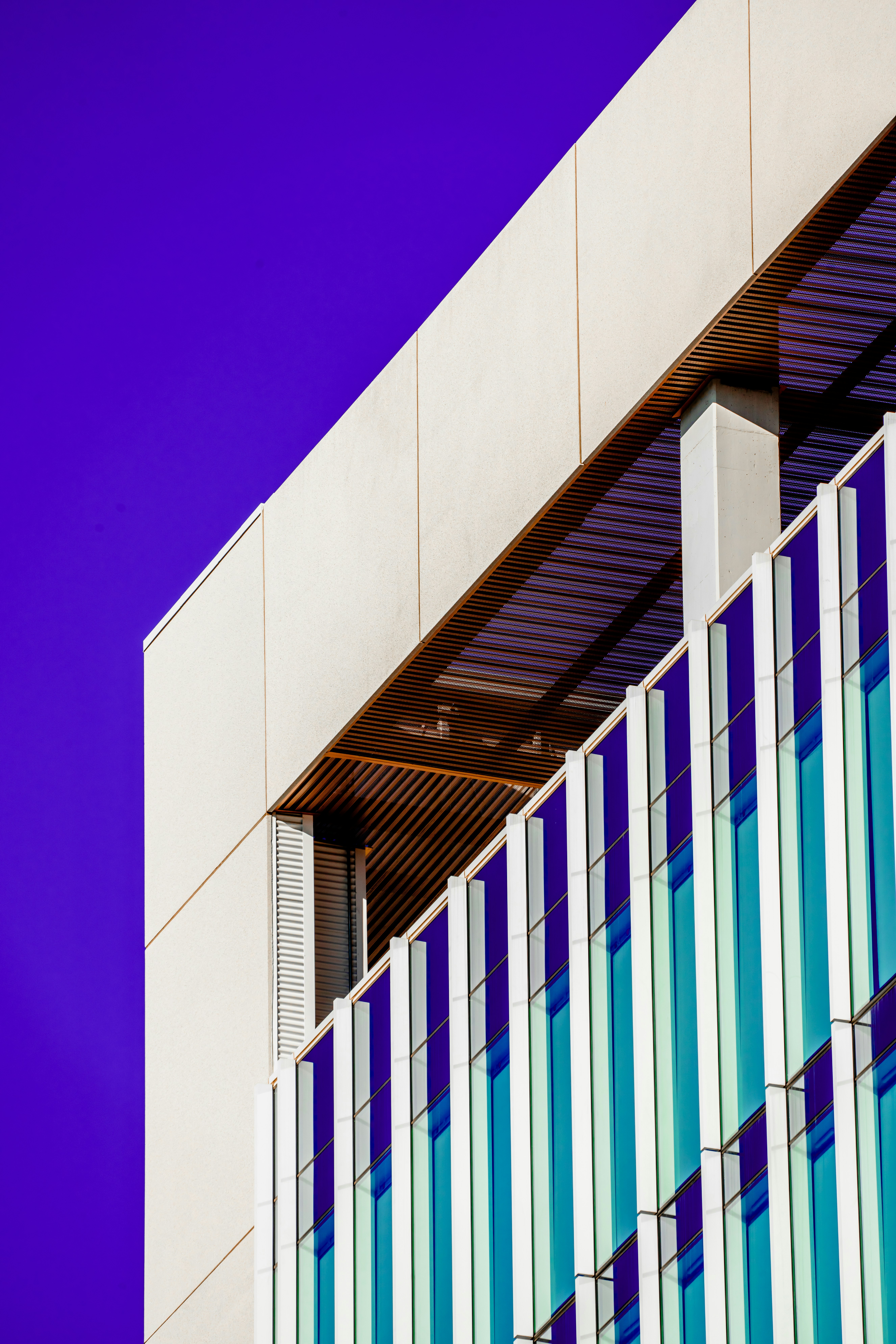 Meritt Thomas on Unsplash Tall building with vertical column windows against a bright purple background.